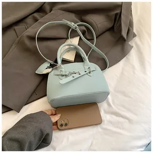 Détail du sac à main bleu menthe avec texture grainée et pendentif en forme de cœur