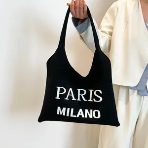 Detail van zwarte gebreide shopper met witte Paris Milano belettering en textuur