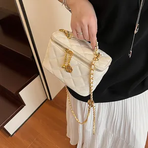Gros plan du sac matelassé blanc avec bandoulière dorée et pendentif rose