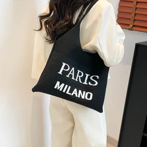 Gedetailleerde gebreide textuur van een zwarte draagtas met witte PARIS en MILANO tekst