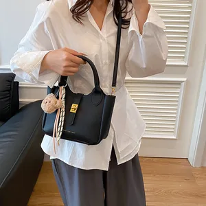 Détail du sac seau noir grainé avec fermoir doré, écharpe en soie et porte-clés ours