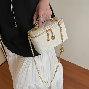 Détail du sac matelassé blanc avec breloques fleurs dorées et fermeture éclair double