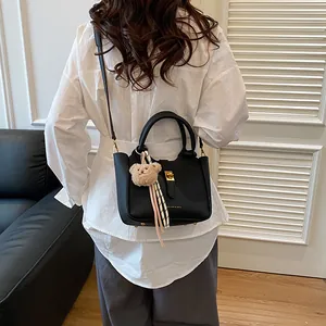 Détail du sac seau noir en cuir grainé avec fermoir doré et breloque ours en peluche
