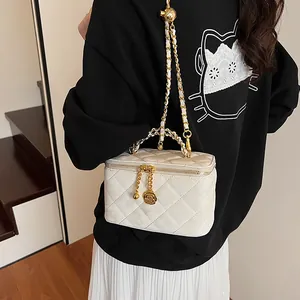 Détail du sac matelassé blanc avec breloque rose dorée porté avec une tenue décontractée