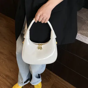 Detail of white patent leather crescent bag with unique gold metallic ball zipper