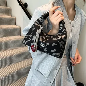 Detail of silver leopard print hobo bag with red heart charm and metallic tassel