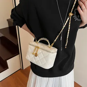 Détails d'un vanity-case blanc matelassé avec pendentif rose dorée et bandoulière