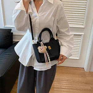 Détail du sac seau noir en cuir grainé avec fermoir doré et pendentif ours en peluche