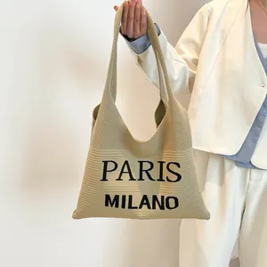 Detail van de kaki gebreide draagtas met zwarte Paris Milano tekst en geweven textuur