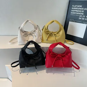 Selection of chic leather handbags in white, yellow, black, and red with bow drawstring detail