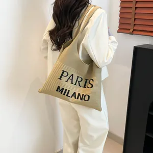 Detailweergave van beige gebreide draagtas met verticale strepen en PARIS MILANO tekst