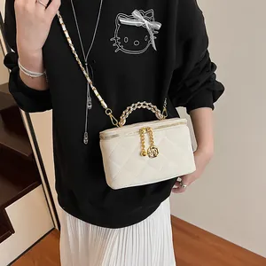 Détail du sac boîte matelassé blanc avec chaîne dorée et pendentif rose sur modèle