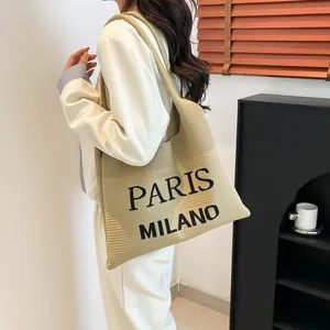 Detail van de grote beige gebreide shopper met Paris Milano tekst gedragen door model