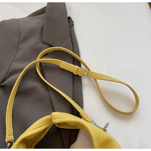 Detail of yellow lychee-textured leather bag showing silver metal buckles and shoulder strap