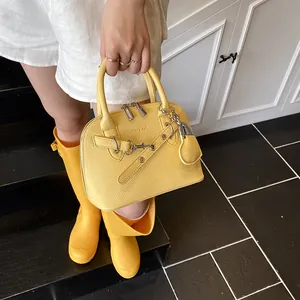 Détail du sac à main en cuir litchi jaune avec breloque cœur et boucles décoratives