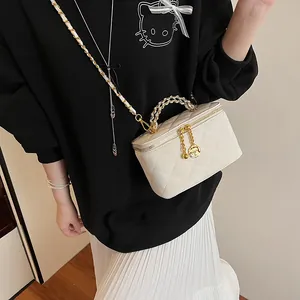 Détail du sac bandoulière blanc matelassé avec poignée chaîne dorée et breloques fleurs
