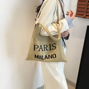 Detail van gebreide shopper met Paris Milano tekst en verticale geribbelde textuur
