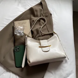 Close-up of cream leather shoulder bag with distinct gold curved metal buckle detail