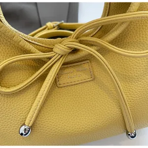 Detail of yellow lychee grain leather handbag with bow drawstring and silver metal ball