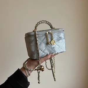 Détail du vanity matelassé argenté avec poignée chaîne et breloque rose dorée au zip