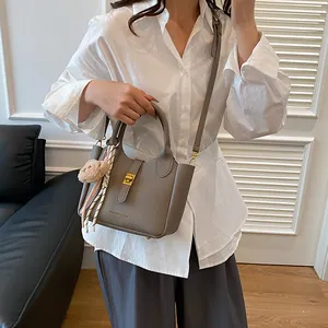 Détail du sac seau en cuir gris avec fermoir doré, foulard en soie et breloque ours