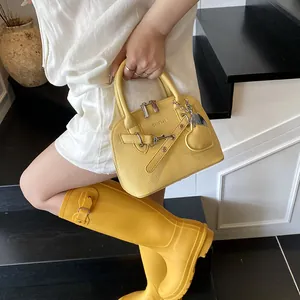 Détail du sac à main jaune texture litchi avec bottes de pluie assorties sur l'escalier
