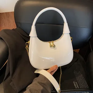 Detail of white glossy hobo bag with gold ball zippers and detachable chain strap