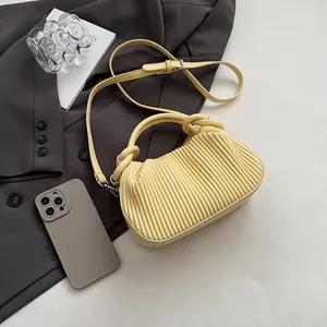 Détail d'un sac bandoulière jaune pâle avec texture plissée verticale et poignée nouée