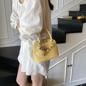 Détail du sac coquille jaune avec texture grainée et accessoire de charme en forme de cœur