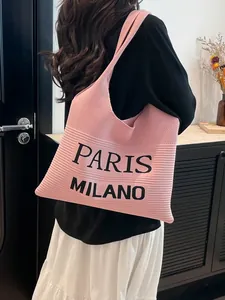 Roze gebreide shopper met Paris Milano opdruk gedragen door een model in een stadse setting
