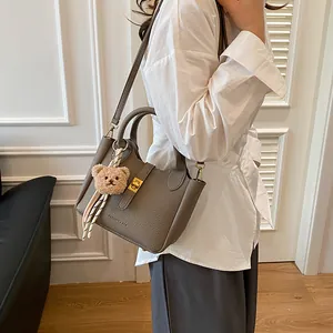 Détail du sac à main en cuir gris foncé avec pendentif ours et fermoir doré rotatif