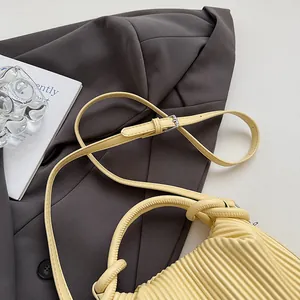Détail du sac plissé jaune crème avec poignée nouée et boucles métalliques de sangle