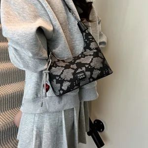 Detail of grey leopard print dumpling bag with red heart charm and tassel accent