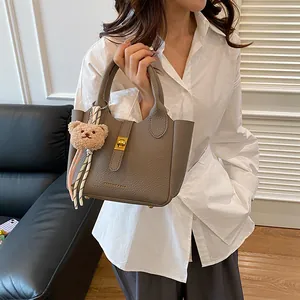 Détail du sac seau en cuir taupe avec fermoir doré et décoration de foulard en soie