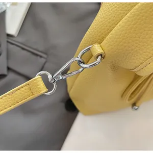 Detail of silver metal hook and yellow litchi grain leather strap on handbag