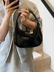 Glossy black patent leather crescent moon bag with gold chain strap for crossbody wear