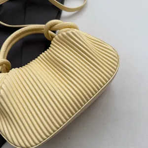 Détail du sac à main jaune crème montrant la texture plissée et l'anse en corde nouée