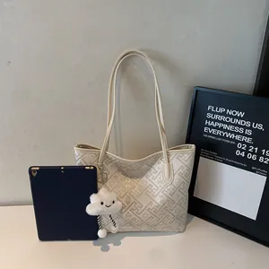 Dettaglio della borsa tote jacquard crema con motivo geometrico e ciondolo a nuvola