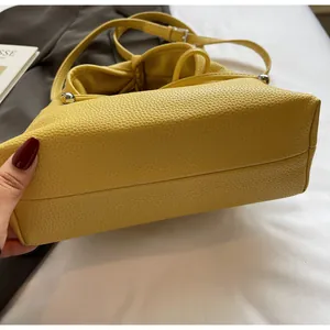 Detailed view of yellow lychee grain leather texture and stitching on crossbody bag