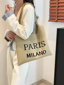 Grote beige gebreide tote bag met Paris Milano tekst gedragen door een model