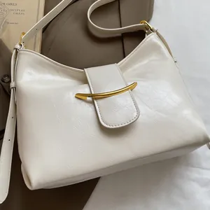 Detailed close-up of cream textured leather bucket bag with elegant gold crescent hardware