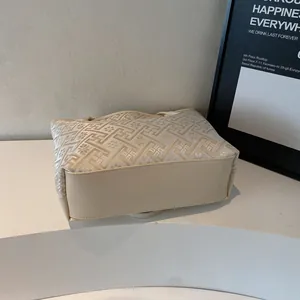 Dettaglio della borsa tote in jacquard beige con motivo floreale su un supporto minimal