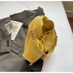 Detail of bright yellow leather handbag showing textured grain and silver metal hooks