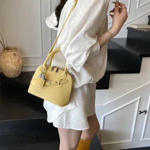 Détail du sac à main jaune avec lanières en cuir et rivets métalliques sur modèle