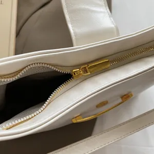 Detailed close-up of premium white bucket bag with golden zipper and herringbone lining