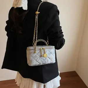 Détail du sac boîte argenté matelassé avec bandoulière chaîne dorée et fini métal