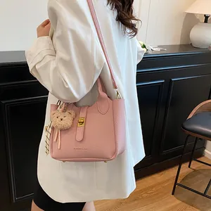 Vue latérale d'un sac seau rose clair avec breloque ours sur un mannequin en blanc