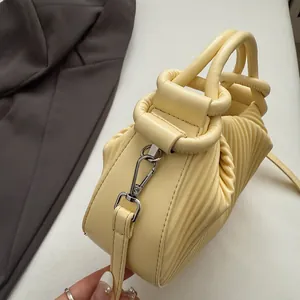 Gros plan du sac à main plissé jaune pâle avec poignée design en cuir et crochets en argent
