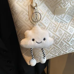 Vista dettagliata del ciondolo a nuvola in peluche con sorriso su una borsa decorata