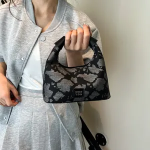 Close-up of black and silver cow print handbag with branded logo patch and leather handles